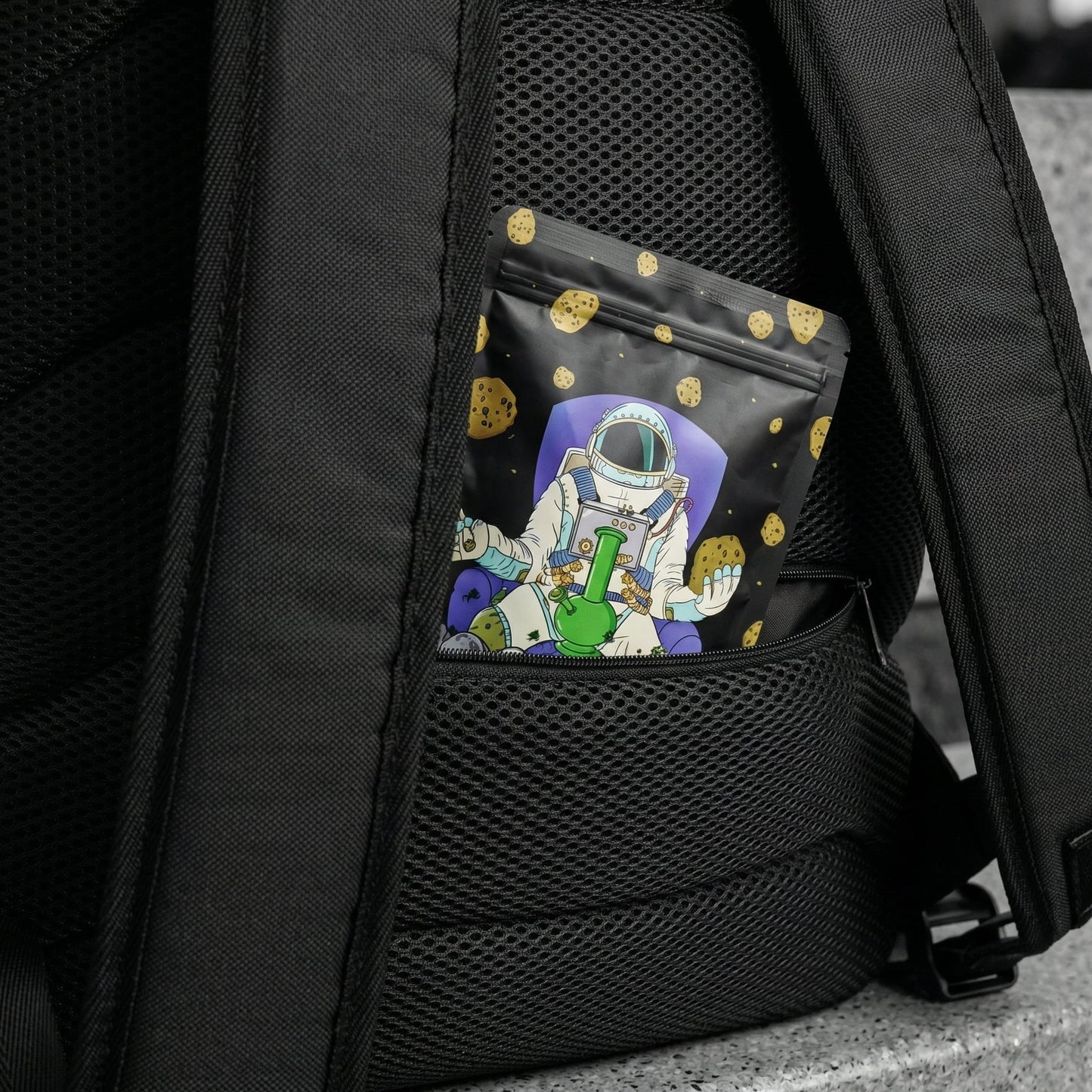 Macro close-up of NGU backpack secret anti-theft lumbar pocket on back mesh, showing scale with Mylar bag insert, Noir selective color.