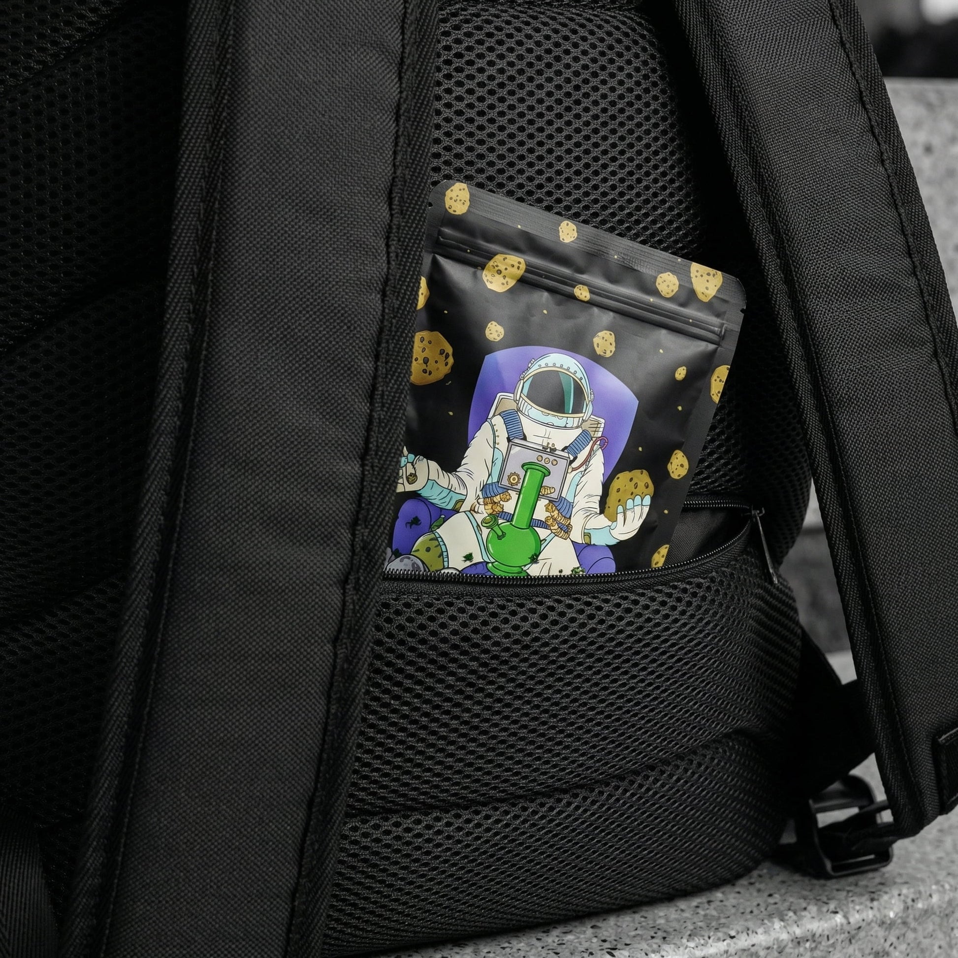 Macro close-up of NGU backpack secret anti-theft lumbar pocket on back mesh, showing scale with Mylar bag insert, Noir selective color.