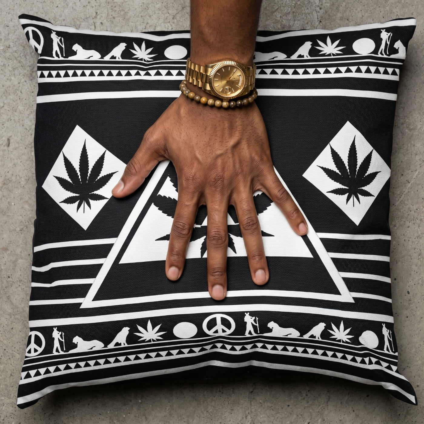 Macro shot of a mocha-skinned hand with a gold fluted watch pressing into the center of the Black and White NGU Architect pillow, creating realistic fabric tension and compression on the 275gsm canvas.