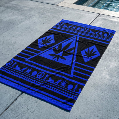 Angled view of the Black and Electric Blue NGU Architect Towel on a concrete surface. The perspective emphasizes the Sovereign Scale of the 36x72 towel, featuring high-contrast blue architectural line-art against a deep matte-black heavyweight cotton base.