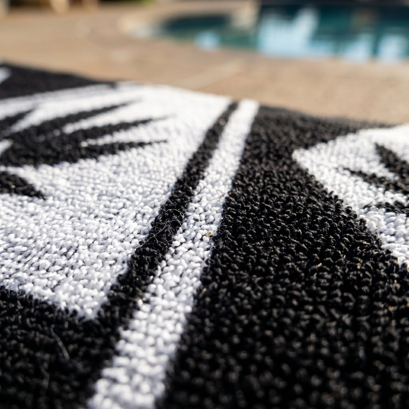 Macro close-up of the NGU Architect Towel emphasizing the heavy 360gsm looped cotton texture. The white geometric lines of the design are vector-sharp and crisp against the high-frequency topography of the black fabric. Soft natural lighting reveals deep, authentic folds and material density.
