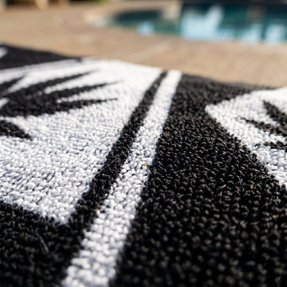 Macro close-up of the NGU Architect Towel emphasizing the heavy 360gsm looped cotton texture. The white geometric lines of the design are vector-sharp and crisp against the high-frequency topography of the black fabric. Soft natural lighting reveals deep, authentic folds and material density.