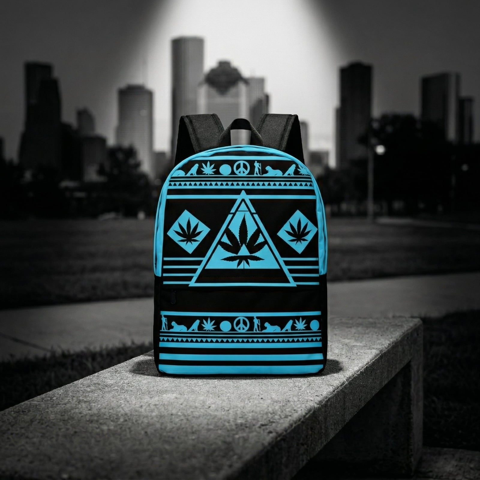 Wide shot of the NGU Gamma Blue backpack resting on a concrete surface in an urban park setting with a monochromatic city skyline background.