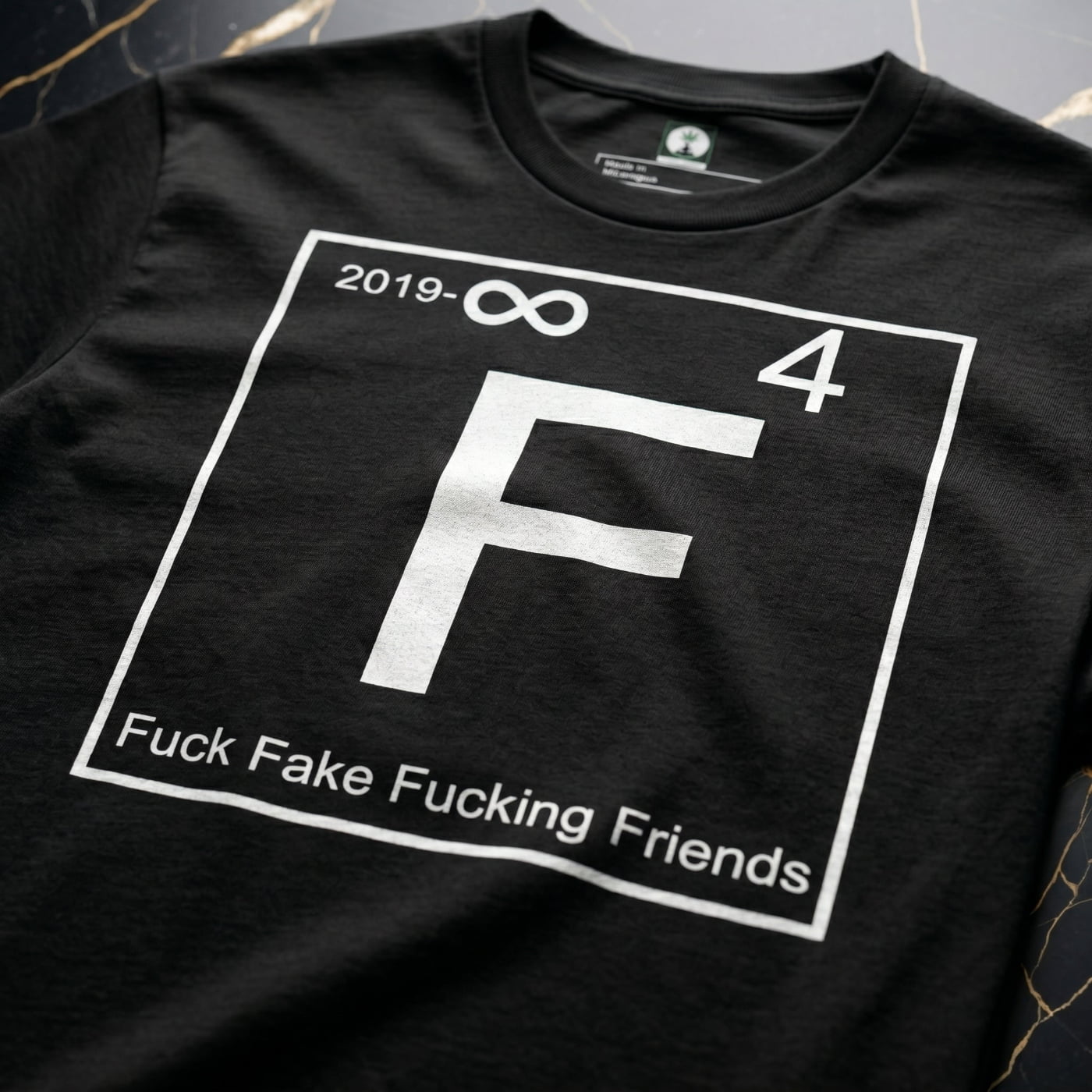 Close-up of the white periodic table "F" graphic on NGU "Fuck Fake Fucking Friends" 400gsm matte-weave cotton, showcasing high-density fabric texture