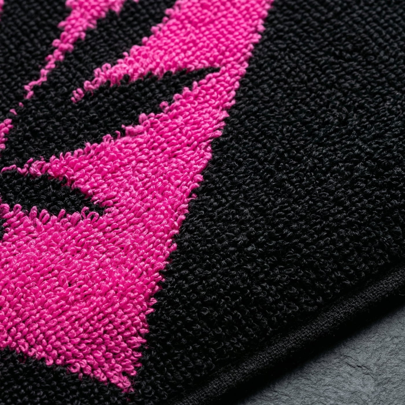 Macro texture shot of NGU Sanctuary towel showing high-density 400gsm looped-pile cotton in black and pink; premium cannabis lifestyle textile detail