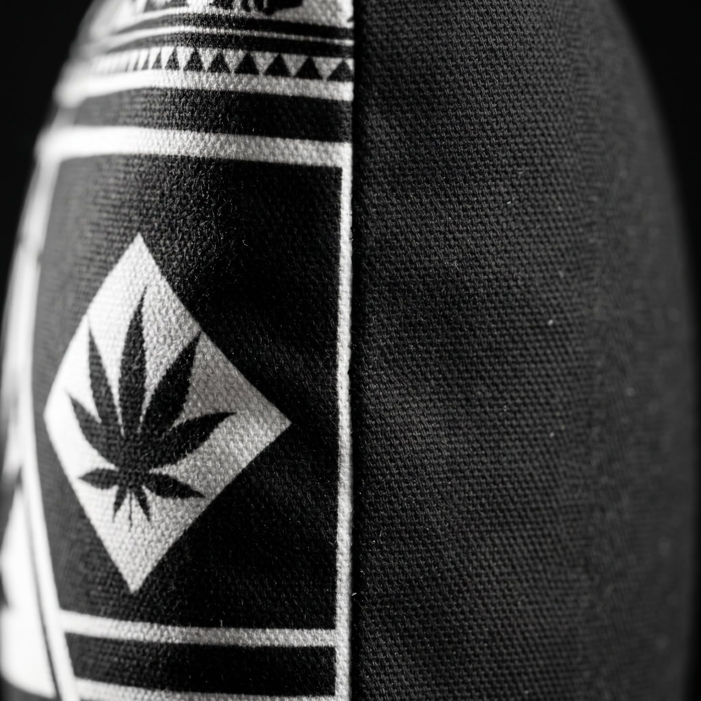 Side-angle detail of the Black and White NGU Architect pillow showcasing the thick 275gsm canvas texture and the vector-sharp white weed leaf alignment on the matte-black fabric.